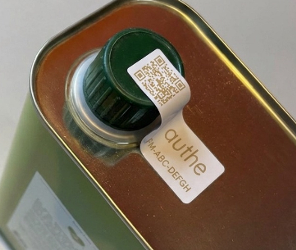 An authe seal over the cap of a family. nostalgia olive oil tin: a QR code, the authe name and the code FM-ABC-DEFGH